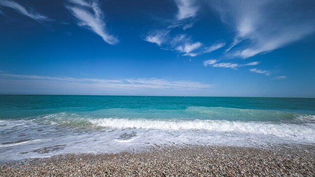 Ein Strand mit klarem Himmel und ruhiger Brandung.