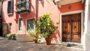 Un cortile con una pianta in vaso, una porta in legno e un edificio con un balcone.