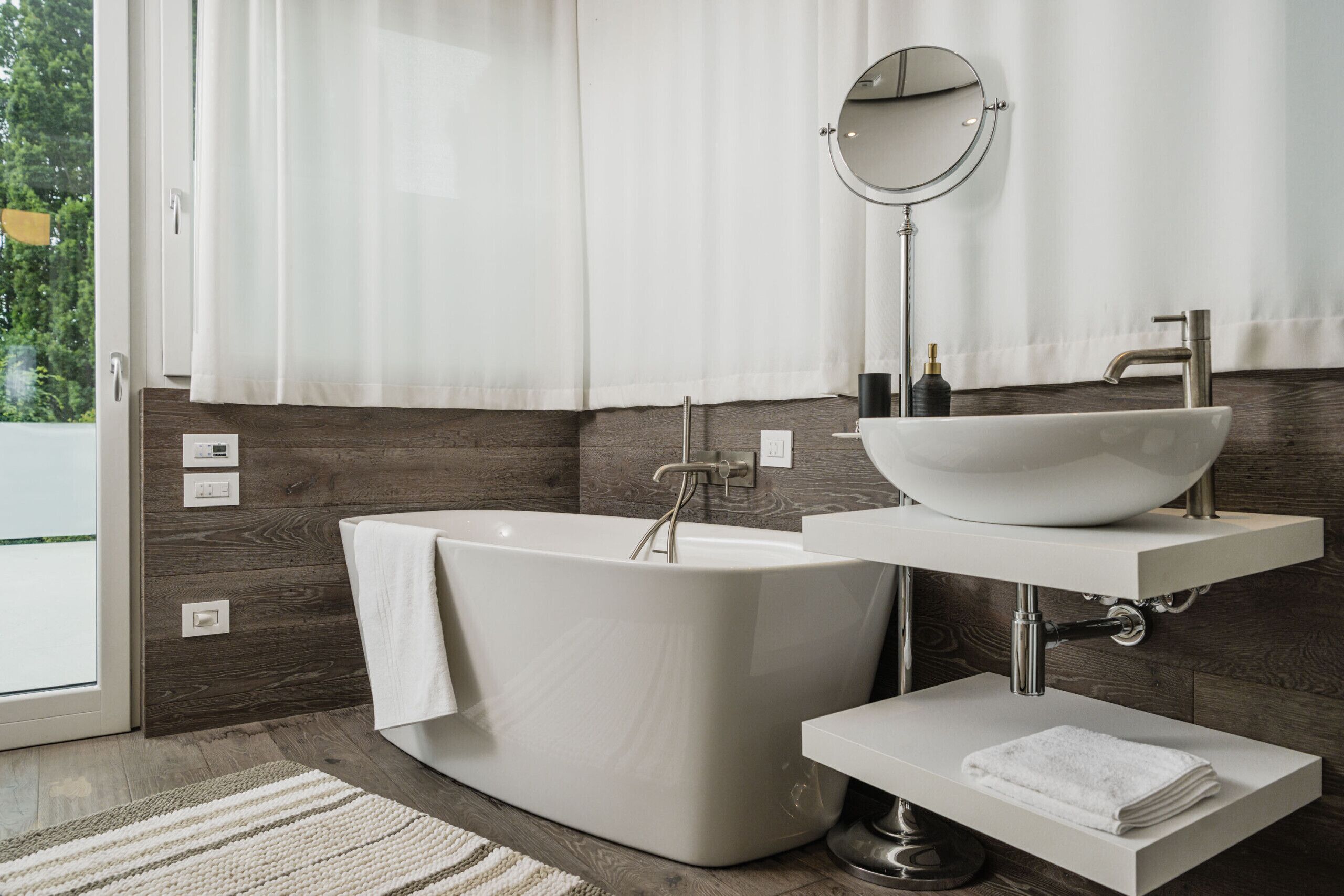 A modern bathroom with a freestanding bathtub, a vessel sink, and a mirror above the sink.