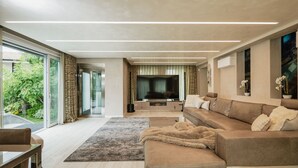 Una sala de estar moderna con sofá, televisor y vistas al exterior.