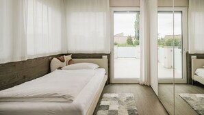 Un dormitorio con cama, ventana grande y vista al exterior.