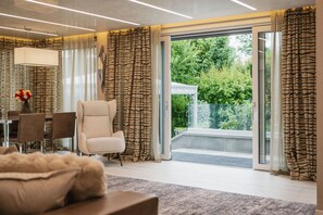 A modern living room with a sofa, armchair, and dining table. - 630A Luxury Villa Scherlin (Bardolino)