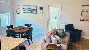 Ein Zimmer mit Esstisch, Stühlen, einer Couch, einer Lampe und einem Bild an der Wand.