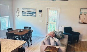 Ein Zimmer mit Esstisch, Stühlen, einer Couch, einer Lampe und einem Bild an der Wand.