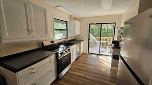 A modern kitchen with a built-in oven, a stainless steel refrigerator, and a sliding glass door leading to an outdoor deck. - 3-Bedroom private lake cabin with access to state park and boat ramp (Pittsburg)