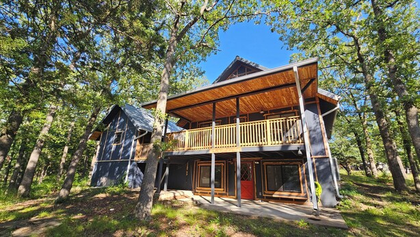 A wooden cabin with a balcony, surrounded by trees. - 3-Bedroom private lake cabin with access to state park and boat ramp (Pittsburg)
