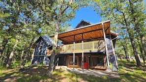 A wooden cabin with a balcony, surrounded by trees.