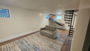 A living room with a sofa, a hammock, a staircase, and a window.