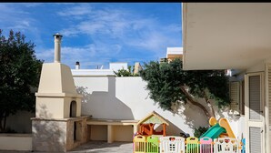 A courtyard with a chimney, play area, and a white wall.