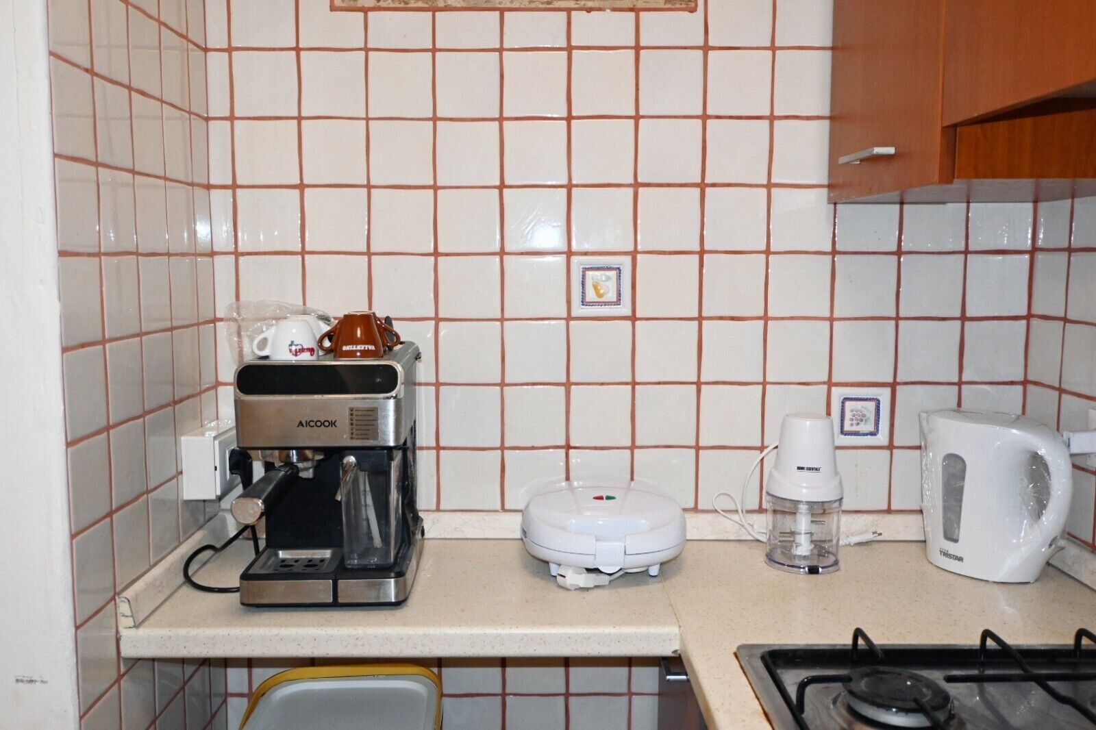 Een keuken met een koffiezetapparaat, waterkoker en broodrooster op het aanrecht.