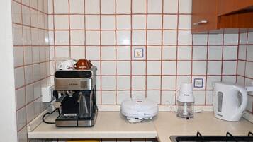 Een keuken met een koffiezetapparaat, waterkoker en broodrooster op het aanrecht.