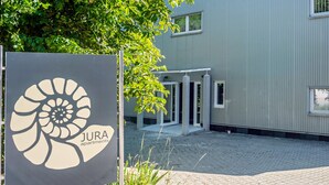 JURA-huoneistojen kyltti, taustalla moderni rakennus.