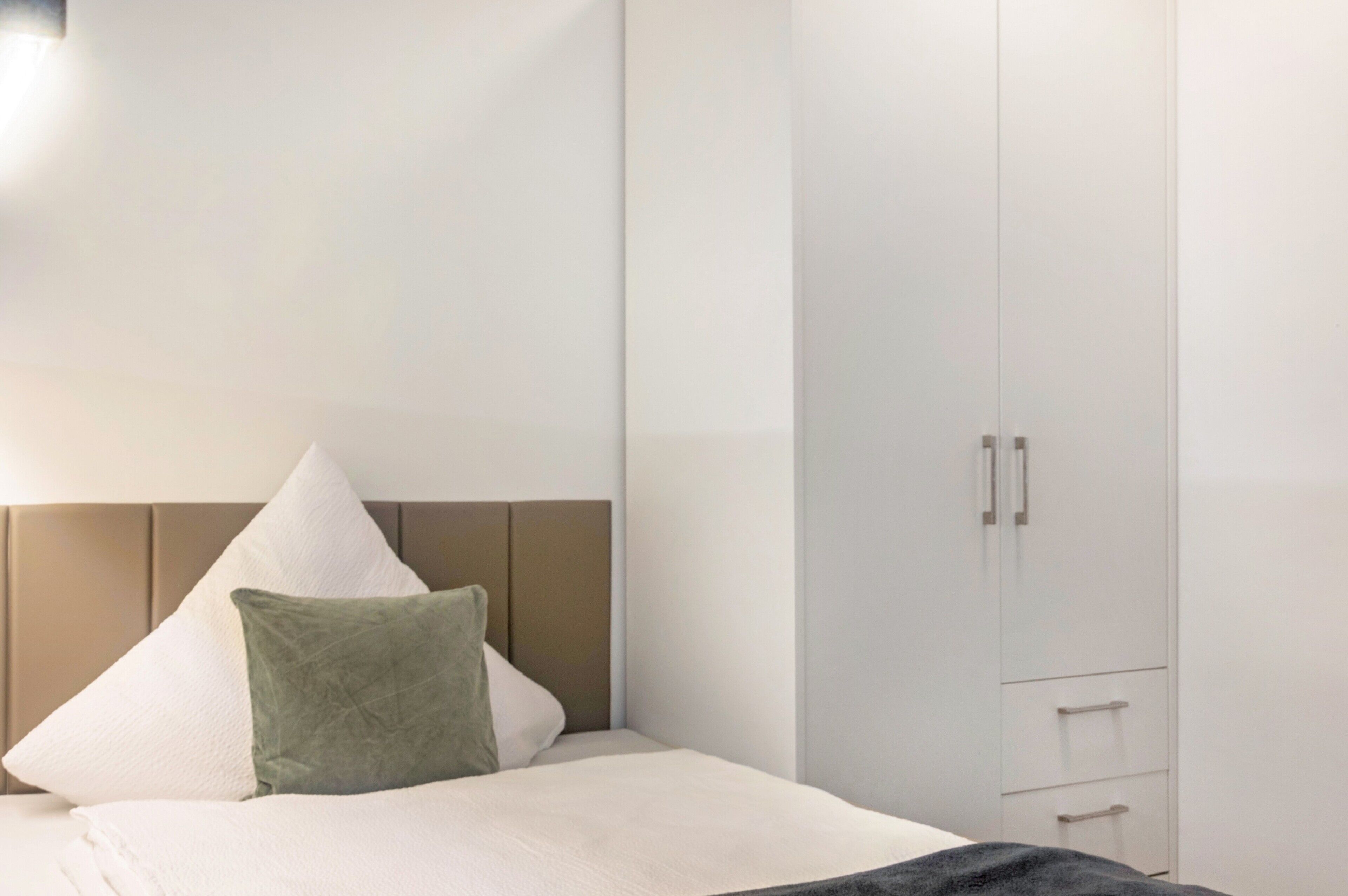 Ein Schlafzimmer mit Bett, Kissen, Kleiderschrank und Nachttisch.