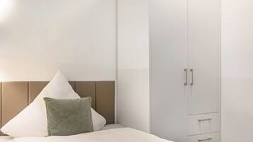 Ein Schlafzimmer mit Bett, Kissen, Kleiderschrank und Nachttisch.