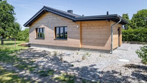 A modern wooden house with a sloped roof, two windows, and a paved driveway. - Exclusive vacation home in first occupancy with unobstructed views of the Salzhaff (Am Salzhaff OT Pepelow)