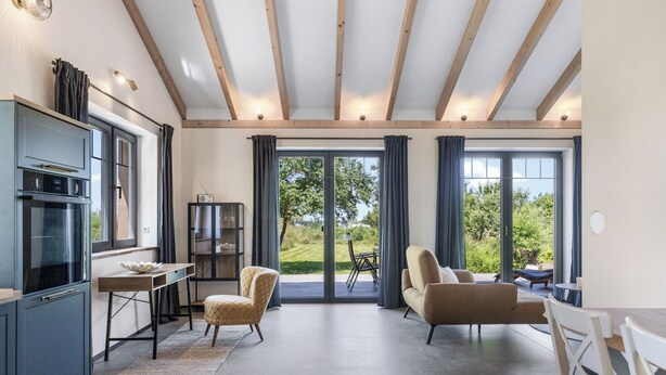 A modern kitchen with built-in appliances, a dining area with a table and chairs, and a large sliding glass door leading to an outdoor patio. - Exclusive vacation home in first occupancy with unobstructed views of the Salzhaff (Am Salzhaff OT Pepelow)