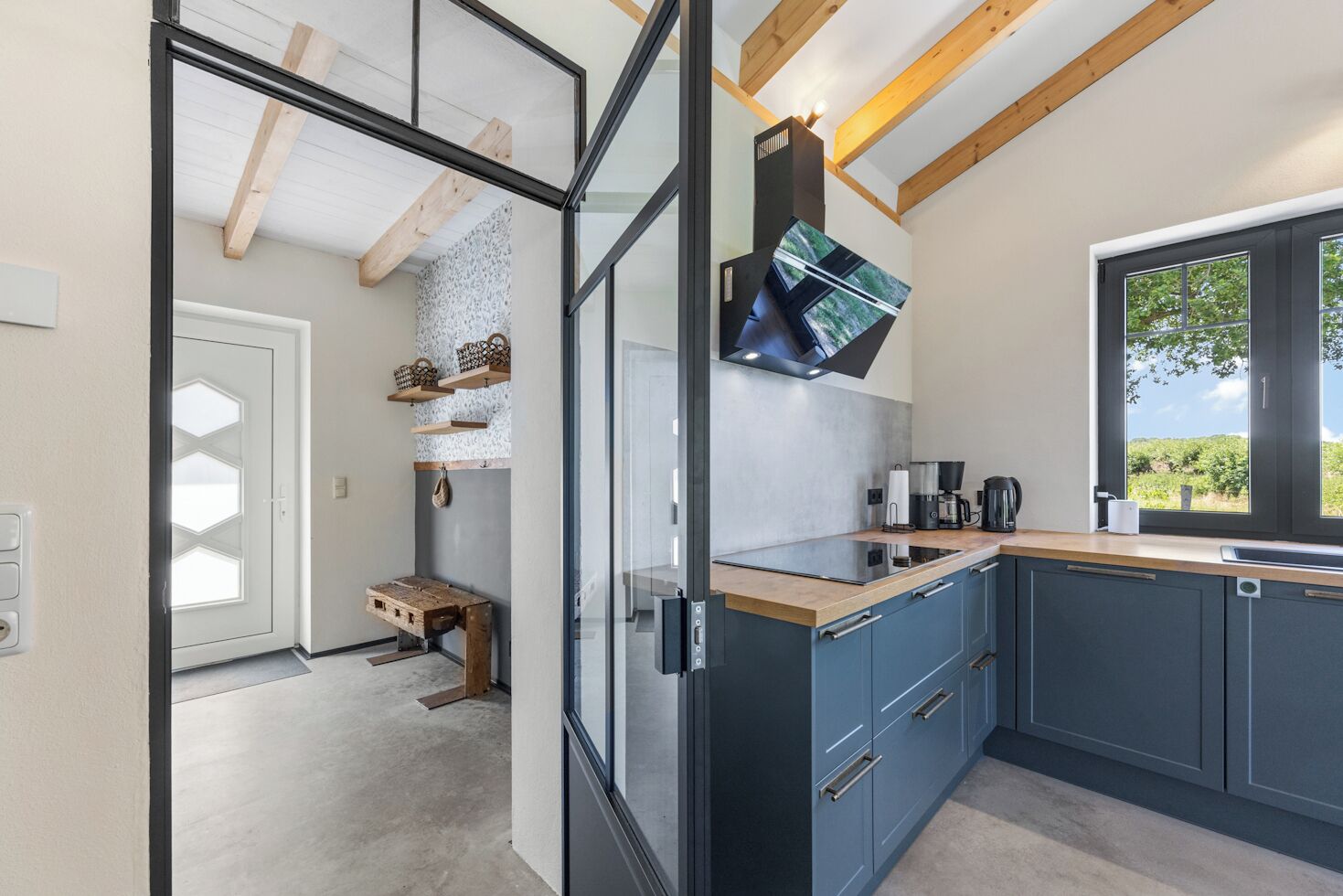 A modern kitchen with a built-in stove, a window with a view, and a wooden bench.
