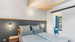 A modern bedroom with a bed, bedside tables, and a view of the outdoors. - Exclusive vacation home in first occupancy with unobstructed views of the Salzhaff (Am Salzhaff OT Pepelow)