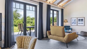 A modern interior with large windows, a sofa, a chair, and a table. - Exclusive vacation home in first occupancy with unobstructed views of the Salzhaff (Am Salzhaff OT Pepelow)