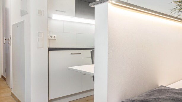 Una cucina moderna con pensili bianchi, un piano di lavoro e un forno integrato.
