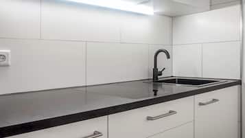 A modern kitchen with white cabinets, a black countertop, and a black faucet.