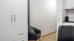 Et moderne køkken med hvide skabe, en sort stol og en bordplade med en kaffemaskine.