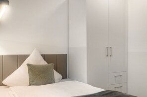 A modern bedroom with a bed, a wardrobe, and a nightstand.