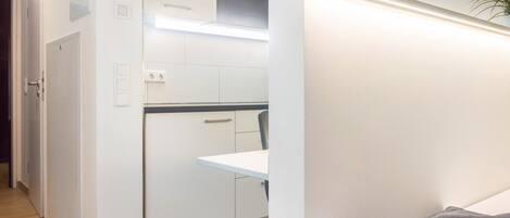 A modern kitchen with white cabinets, a countertop, and a built-in oven.
