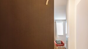 A hallway with a brown wall, a red chair, and a white door. - Studio Apartment '7' with Wi-Fi (Parsberg)