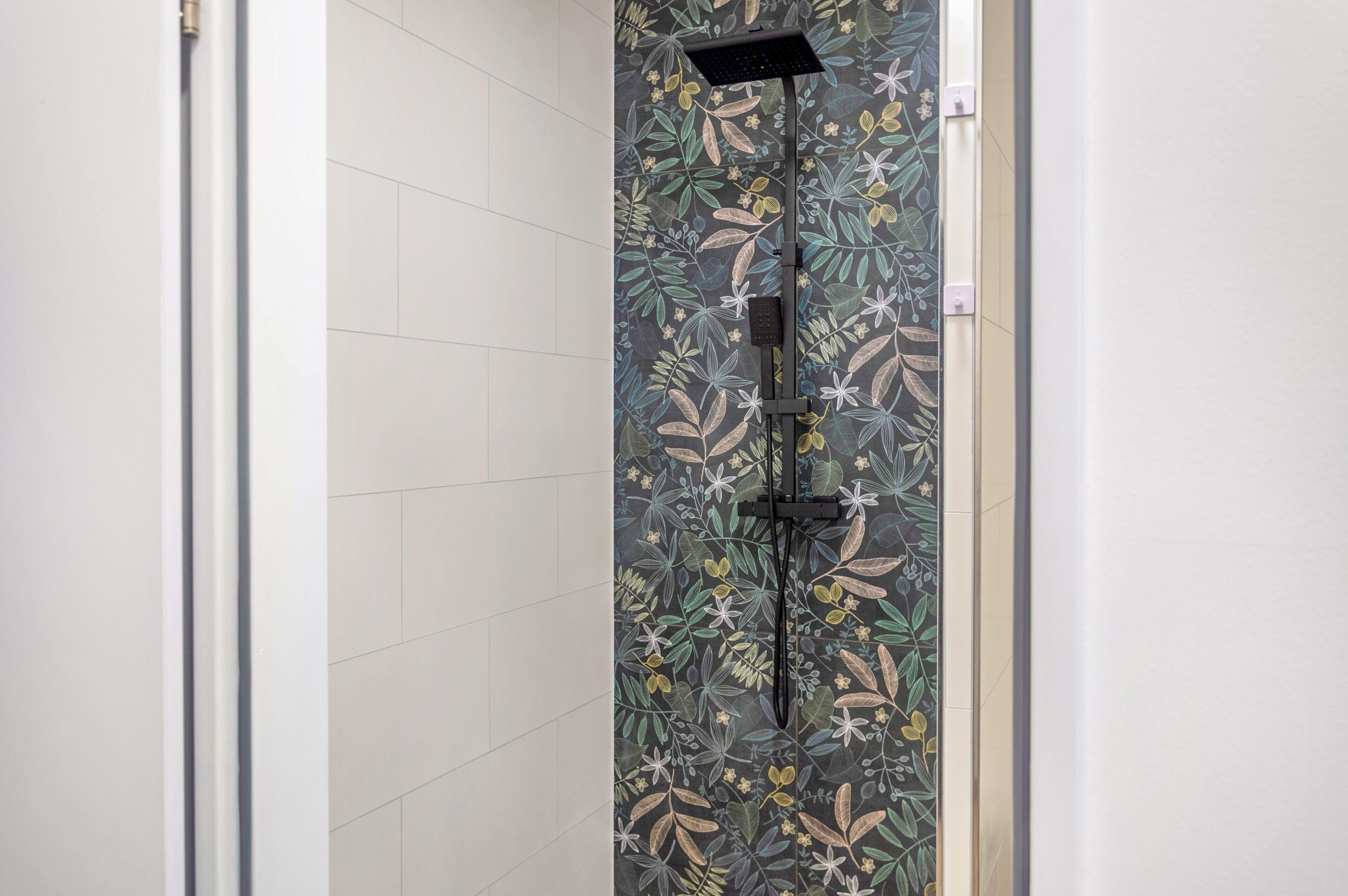 Een douche met een bloemmotief op de tegels en een moderne kraan.