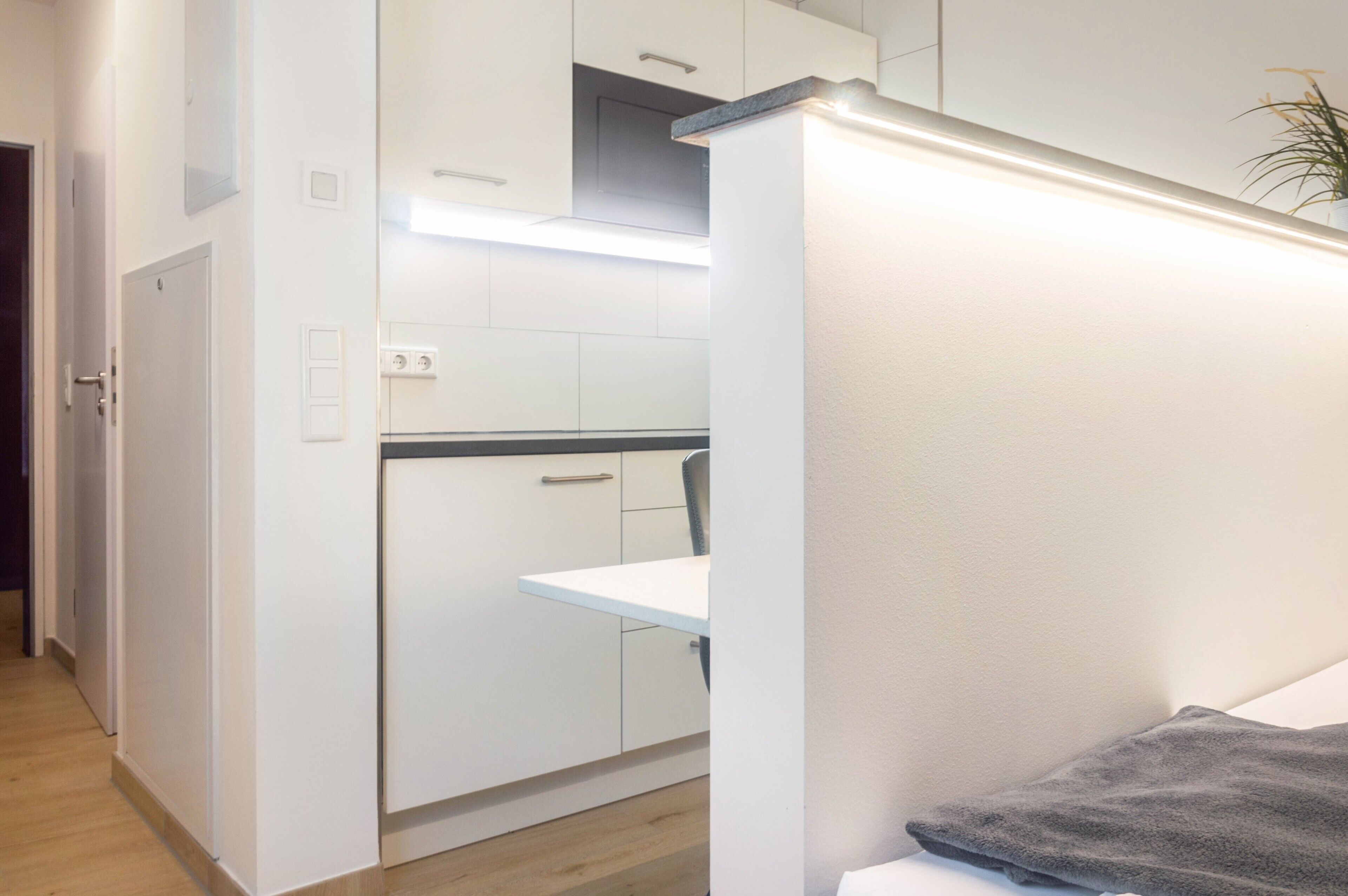 Una cocina moderna con gabinetes blancos, una encimera y un horno empotrado.