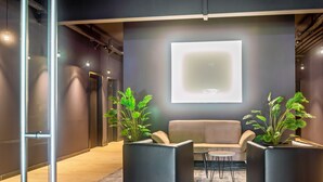A modern lobby with a sofa, two potted plants, a small table, and a large illuminated screen on the wall. - Studio Apartment '8' with Wi-Fi (Parsberg)