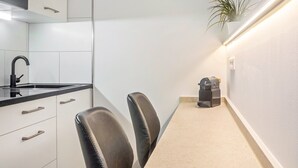 A modern kitchen with a black faucet, white cabinets, two leather chairs, a countertop, and a plant. - Studio Apartment '8' with Wi-Fi (Parsberg)