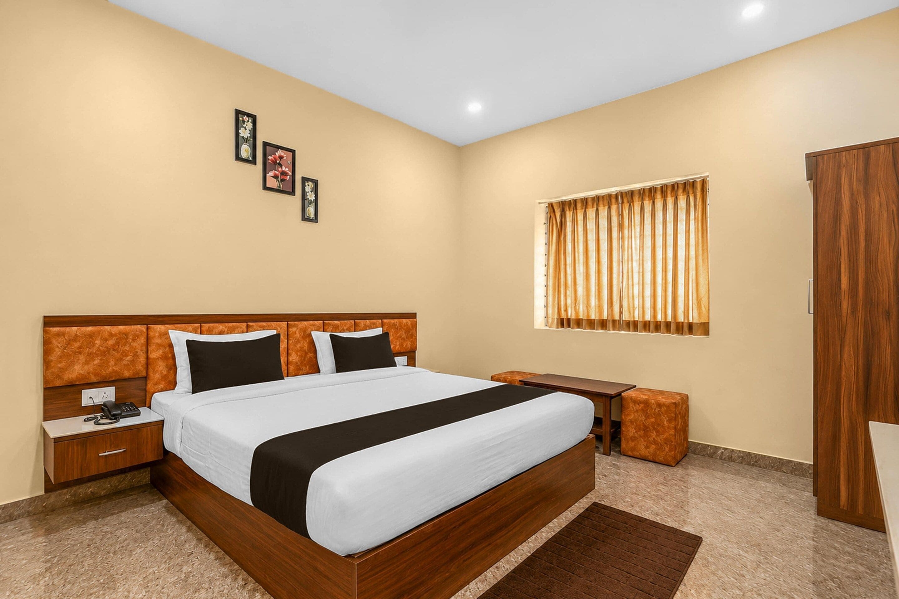 A hotel room with a large bed, bedside tables, a desk, and a wardrobe.
