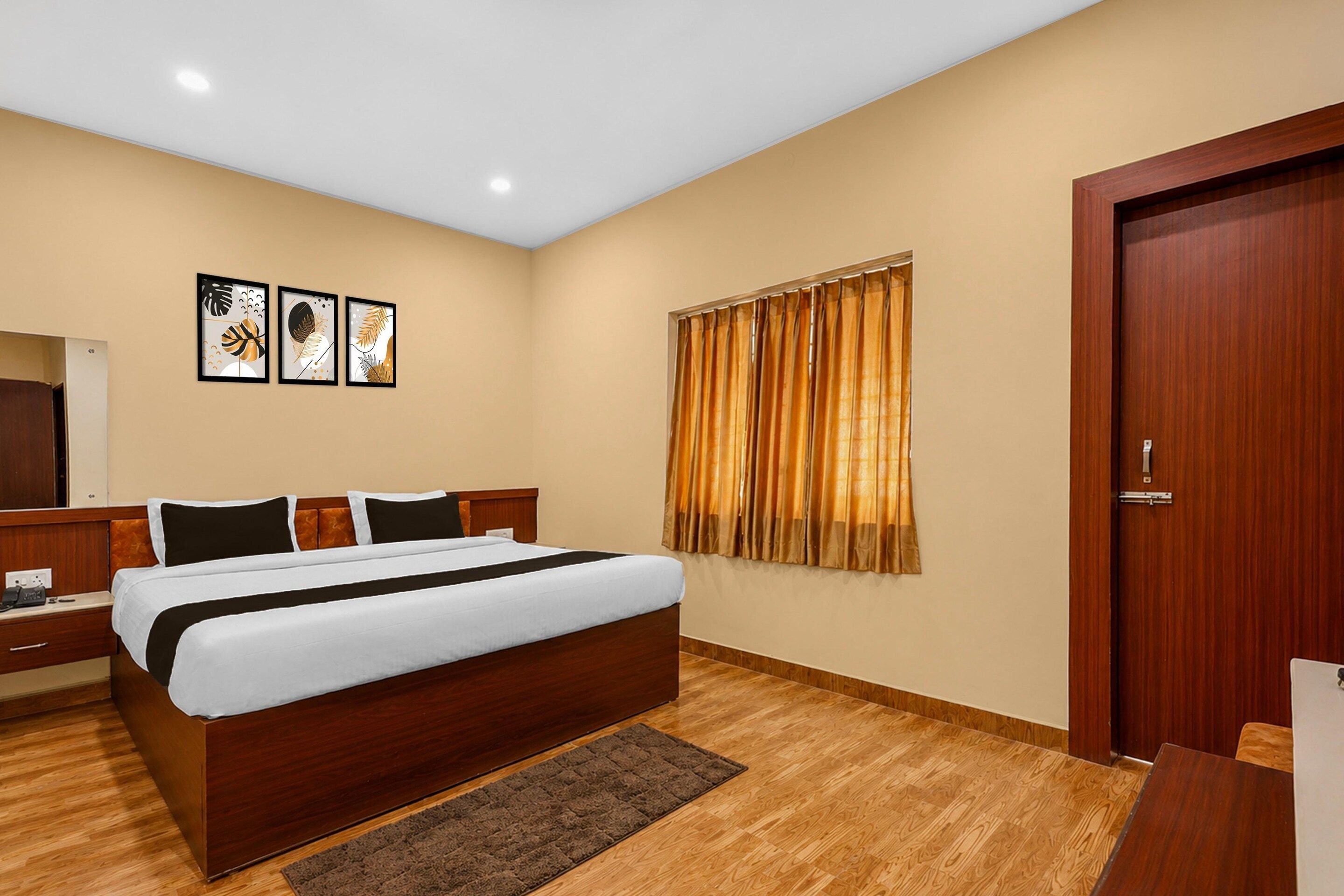 Une chambre d’hôtel avec un grand lit, une tête de lit en bois, une table de chevet, un miroir et une porte.