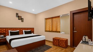 A hotel room with a large bed, bedside tables, a desk with a kettle, and a mirror. - Deluxe JR Royals (Golmuri)