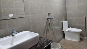 Un baño con lavamanos, inodoro, ducha y espejo.