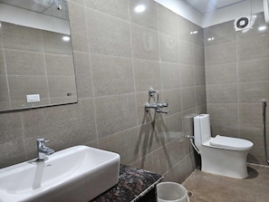 Un baño con lavamanos, inodoro, ducha y espejo.