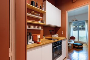 Eine moderne Küche mit weißen Schränken, Holzregalen und einem eingebauten Backofen.
