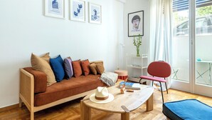 A modern living room with a sofa, a coffee table, a chair, and framed artwork on the wall. - Your Haven in Kolonaki - Your home away from home - Didotou 1Br (Athina)