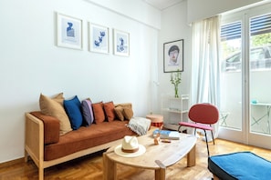 Ein modernes Wohnzimmer mit einer Couch, einem Couchtisch, einem Sessel und gerahmten Bildern an der Wand.