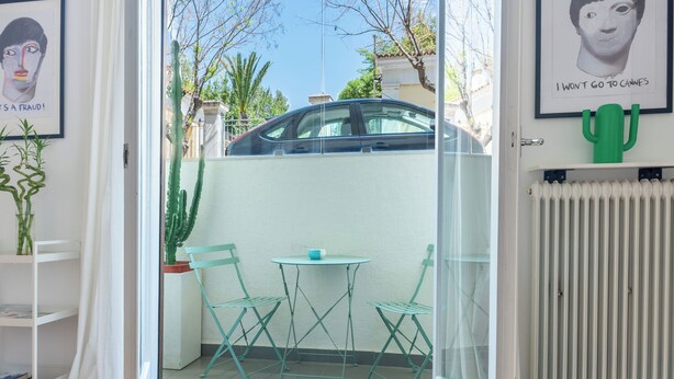 A glass door leading to a patio with a car parked outside, a small table with chairs, and a cactus decoration on the wall. - Your Haven in Kolonaki - Your home away from home - Didotou 1Br (Athina)