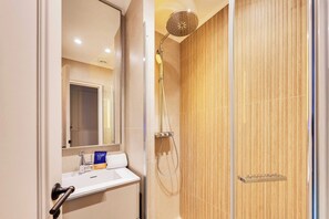 A bathroom with a sink, mirror, shower, and wooden wall. - Charming Apartment a/c 2br/6p - Grand Boulevards (Paris)