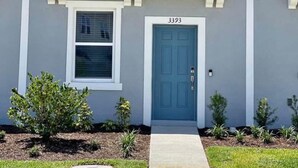 A two-story residential building with a grey facade, white trim, and a blue door. - 2-bedroom, 2/5 bath  townhome in westview  Kissimmee with cool AC, (Kissimmee)