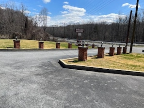 A motel entrance with a sign, brick pillars, and a parking lot.