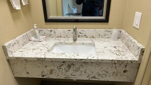 Un baño con lavamanos de mármol, un espejo y un perchero para toallas.