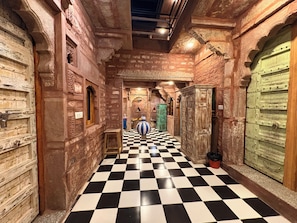 Un pasillo con piso a cuadros, paredes de piedra y puertas tradicionales.