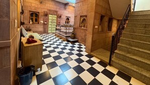 A hotel lobby with a checkered floor, a staircase, and a skylight.