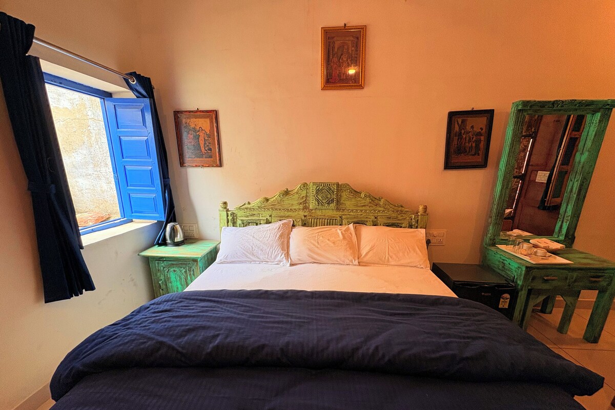Ein Zimmer mit einem Bett, einem Nachttisch, einem Fenster mit Vorhängen und einem Spiegel.