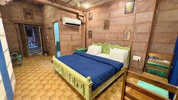 A room with a bed, an air conditioning unit, a ceiling fan, and a small table.
